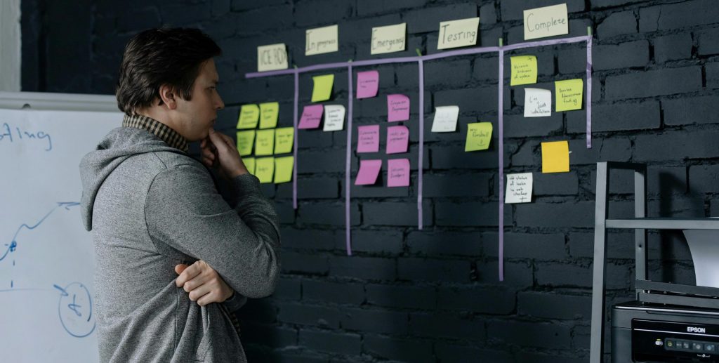Warum sich nichts ändert, obwohl Sie Ihr Problem verstehen. Adult male focusing on task planning using sticky notes on a black wall in a contemporary office setting.