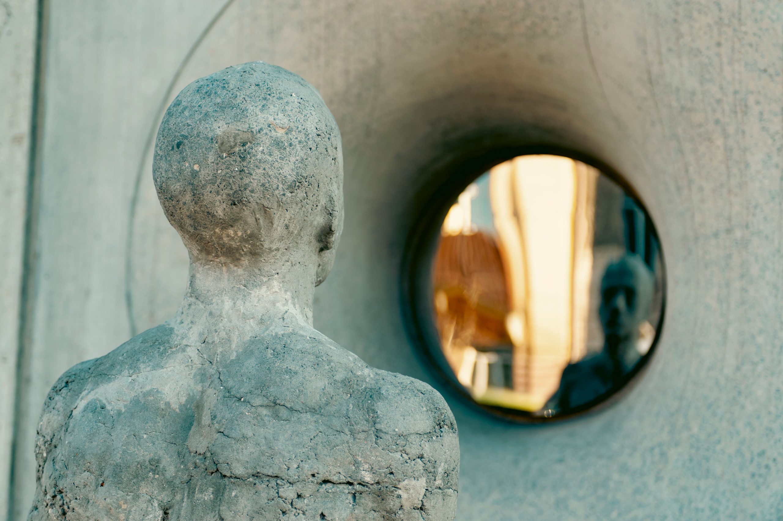 A concrete sculpture reflects in a circular mirror in Lviv, Ukraine, showcasing abstract urban art.
