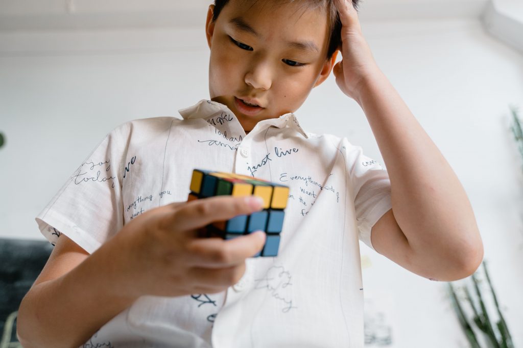 Ein Kind versucht den Rubik's Cube zu lösen. Hier als Versuch das Muster zu durchbrechen.